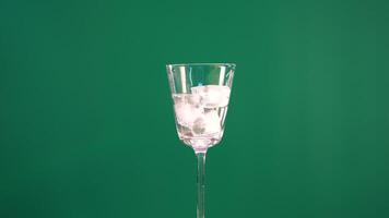 A glass with ice cubes against a green screen background, showcasing minimal movement and consistent lighting video