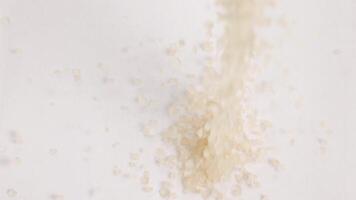 Brown sugar granules cascade onto a pile in a close-up, macro view. The captures the texture and movement vividly video