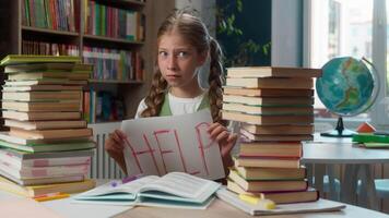 Scared fatigued upset Caucasian little girl child kid schoolgirl school pupil learner student looking camera showing paper sign help too much homework schoolwork overload mental burnout in classroom video