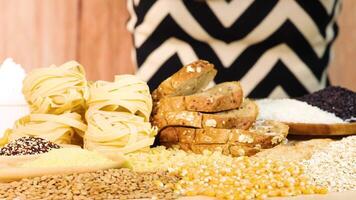 Hands organize various grains and bread slices on a wooden table. Bright lighting enhances the colorful, textured food display video