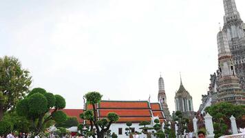 A tranquil scene of Wat Arun temple with lush greenery and cloudy skies, captured in a steady, wide-angle shot video