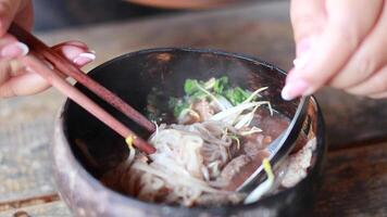 Savoring pork noodles in coconut shell bowl video