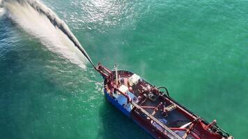 Aerial view of a dredging ship pumping sand into the ocean, enhancing beach restoration efforts under clear skies video