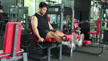 A man performs leg extensions on a machine in a well-lit gym, showcasing strength and focus video