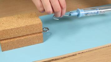 A hand uses a spring scale to measure friction on a wooden block. Bright lighting and close-up focus enhance the experiment video