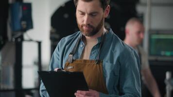 Caucasian man working in factory roasted coffee beans male inspector check roaster machine quality roasting control writing checklist notes guy business owner caffeine roasting production industry video