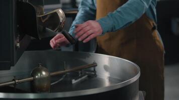 Roasted coffee beans fall out roaster machine hot fresh steam aroma caffeine roasting unrecognizable man guy check quality barista business owner industry working in factory blend roast cropped view video
