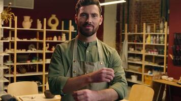 Happy successful Caucasian guy man small business owner smiling businessman potter craftsman crock male looking at camera crossing arms crossed hands gesture career pottery hobby inside workshop store video