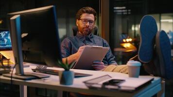Caucasian business man trader businessman analyst writing document in night office paperwork overtime evening working online trading thinking write notes thoughtful guy male developer think ideas task video