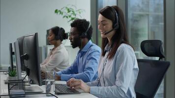Helpline callcenter multiethnic business workers working online computer office customer service call center diverse smiling Caucasian Indian women African man in headset speak work pc helping client video