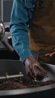 Multiethnic coffee factory workers Caucasian African American men inspecting roasted beans magnifier glass quality aroma flavor checklist clipboard espresso control grind process machine manufacturing video
