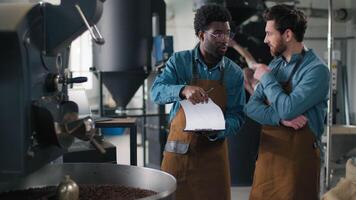 Two multiethnic happy African Caucasian men talking smiling coffee factory inspection checklist quality roaster teamwork supervision coworkers espresso machinery roasting aroma beverage manufacturing video