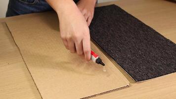 Hands applying adhesive and attaching carpet to cardboard. Step-by-step process with clear, bright lighting and close-up shots video