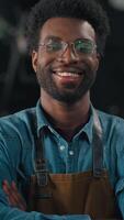 Confident happy smiling African American man worker in coffee roasting fabric crossing hands joyful smile work with roasted cocoa looking at camera indoors male guy professional working distribution video