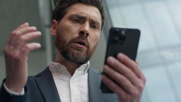Close up unhappy frustrated Caucasian middle-aged business man reading bad news with mobile phone online failure upset in office worried stressed businessman male manager employer smartphone problem video
