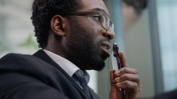 Close up angry emotional stressed African American business man yelling arguing mobile phone call in office ethnic irritated annoyed businessman male guy talking smartphone work problem job quarrel video