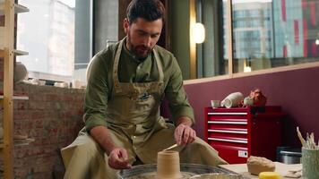 Focused talented happy Caucasian man male guy in apron small business creating master owner artist craftsman potter making handmade sculpt spinning circle wheel shaping clay pottery crockery at studio video