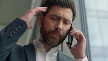 Close up Caucasian businessman worried anxiety business man in office portrait talking mobile phone discuss bad news failure problem communicate male entrepreneur stressed talk call looking in window video