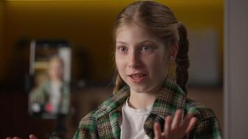 Little girl happy Caucasian influencer streaming live mobile phone online talking blogger teenager child schoolgirl kid record smartphone blog speak chat filming broadcast camera tripod at home video
