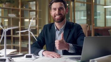 Happy Caucasian business man engineer windmill model working laptop showing thumb up gesture at office businessman male entrepreneur computer recommend approve renewable resources ecology green energy video