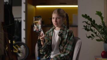Unhappy Caucasian little girl blogger review game app shaking head bad reaction recording blog using mobile phone camera tripod holding new smartphone talking stream influencer kid child at home video