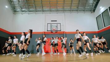 A group of dancers performing a choreographed routine in a basketball gym. The dancers are dressed in stylish athletic outfits, showcasing a mix of energy and precision in their movements. video