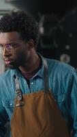 African American man worker in coffee roasting fabric checking roasted cocoa machine smiling at camera posing crossed hands male guy wearing apron working in coffehouse distribution organic production video