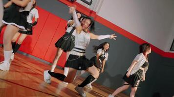 A group of dancers performing a choreographed routine in a gymnasium. They wear stylish outfits with a mix of black and white, showcasing dynamic movements and expressions video