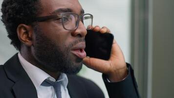 Close up annoyed irritated furious African American business man talking mobile phone shouting yelling problem arguing looking at window in office trouble angry businessman male stress communication video