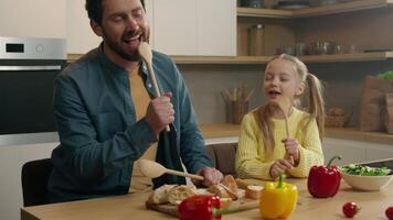 Caucasian relatives single dad parent fatherhood breakfast dinner cooking together food father listen kid girl child daughter singing in spoon like microphone sing having fun at kitchen daddy laughing video
