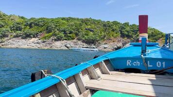 A vibrant boat glides through clear waters near Phuket, Thailand, under bright sunlight with lush greenery in the background video