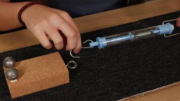 Hands using a spring scale to measure force on a block, illustrating friction on a carpeted surface video