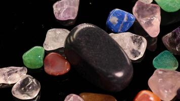 Various chakra stones, including tiger's eye and amethyst, arranged on a black background, showcasing vibrant colors and textures video