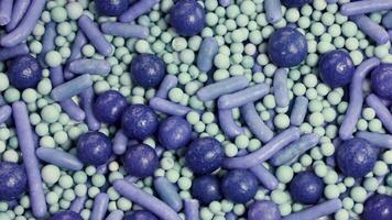 Macro view of purple and green sprinkles rotating, showcasing texture and color in a vibrant, detailed composition video