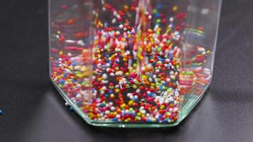 Vibrant sprinkles pour into a clear container video
