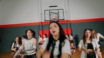 A dynamic dance performance featuring a group of young women in stylish outfits, showcasing energetic choreography in a gymnasium setting with a basketball hoop in the background. video
