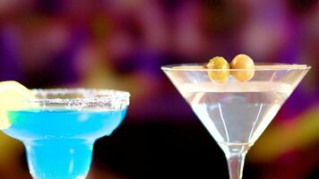 A dynamic showcase of a martini and blue lagoon cocktail against a colorful background, highlighting vibrant colors and elegant glassware video