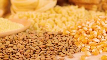 Close-up of various grains, pasta, and sliced whole wheat bread under warm lighting, showcasing texture and detail video