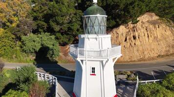 Aerial footage captures the scenic Akaroa Lighthouse surrounded by lush greenery and coastal waters in bright daylight video