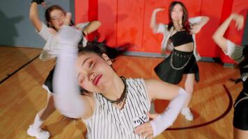 A dynamic dance performance featuring multiple dancers in stylish outfits. The focus is on a dancer with pigtails, showcasing energetic movements in a vibrant studio setting. video