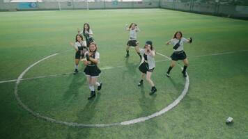 A group of six dancers performing a choreographed routine on a grassy field. They are wearing matching outfits and showcasing dynamic movements, with a focus on teamwork and energy. video