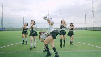 A group of dancers performing on a green turf field, wearing stylish black and white outfits. The scene captures dynamic movements and expressions, showcasing a choreographed routine. video