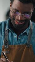 African American ethnic male guy man expert in coffee industry check fresh roasted beans inspecting roasting machine quality of roast in industrial setting writing notes small business cocoa roaster video