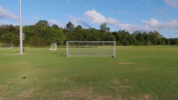 Aerial footage captures a soccer field with a goal, showcasing lush greenery and clear skies in a serene setting video