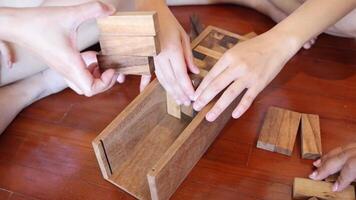 Multiple hands solving a wooden block puzzle together video