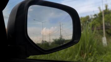 Inside view of mirrors wing. Beside car with green grass. Inside mirror wing with top of grass under the sky. photo