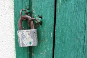 A Rusty Padlock graces the Green Wooden Door, showcasing an intriguing Weathered Texture photo