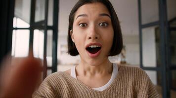 Point of view POV webcam mobile phone happy amazed excited girl Hispanic latin woman astonish wonder shock emotions read good news online app win typing message fingers touch screen display smartphone photo