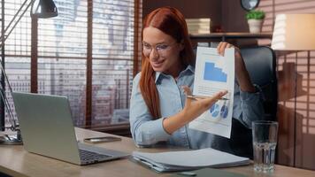 Caucasian businesswoman smiling happy talking call laptop in office showing good results financial grows graphic data marketing success business woman girl female at table virtual consultation photo