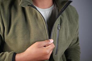 Person adjusting green fleece jacket in indoor setting photo